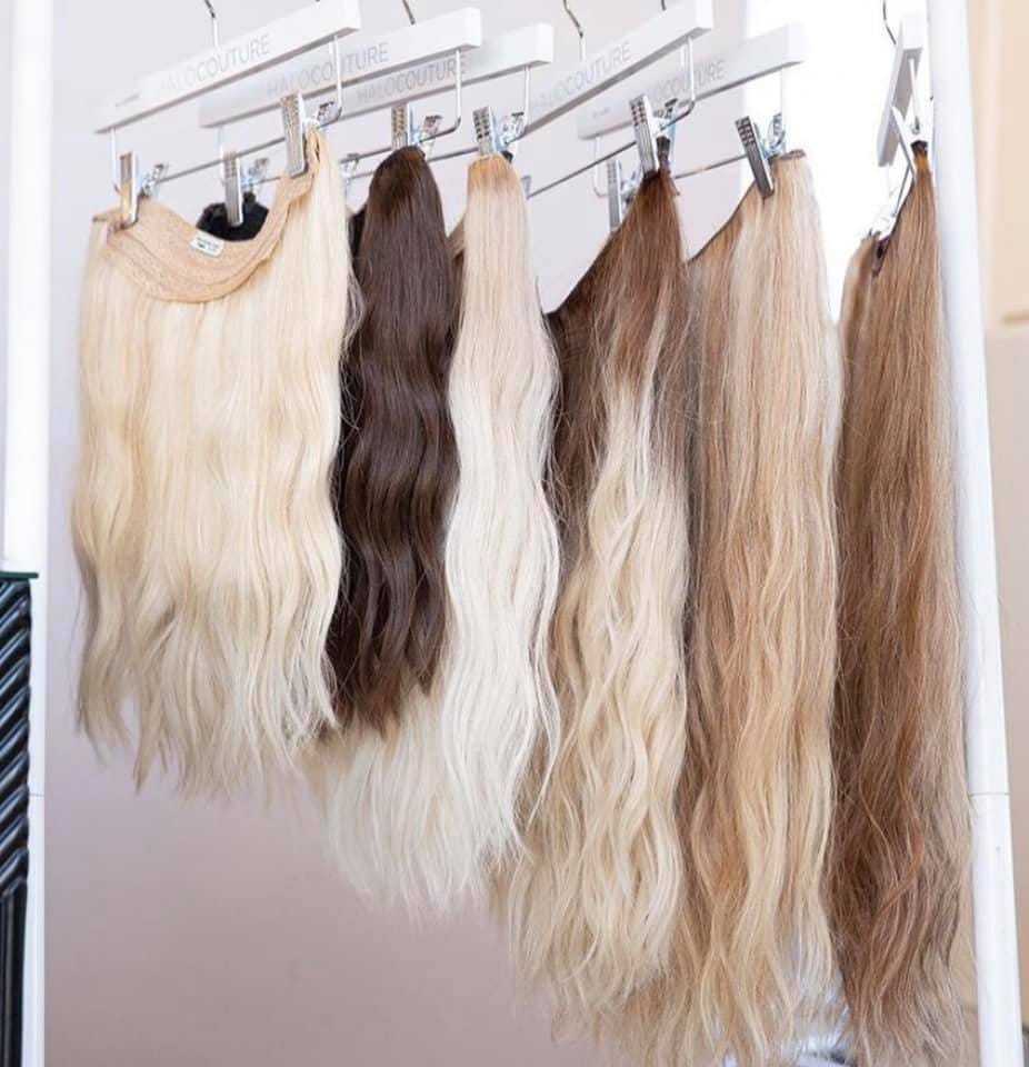 Hair extensions of various shades and styles hanging on display in a store.